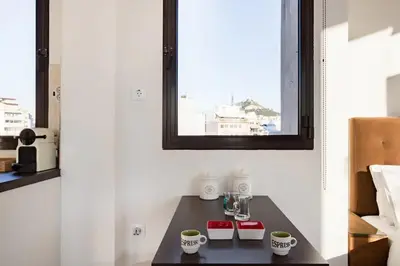 a table with cups on it in a room with a window at Explore Nightlife Near an Apartment With an Acropolis View in Athens