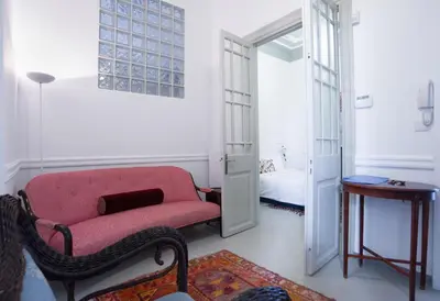 a living room with a red chair and a bed at Neoclassical House at Metro Station Attiki in Athens
