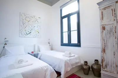 a white room with two beds and a window at Neoclassical House at Metro Station Attiki in Athens