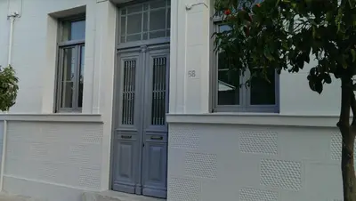 a white building with a blue door and a tree at Neoclassical House at Metro Station Attiki in Athens