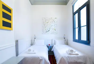 two beds in a room with white walls and windows at Neoclassical House at Metro Station Attiki in Athens