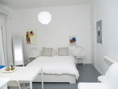 a white bedroom with a white bed and a table at Newly Renovated Apt in Kolonaki in Athens
