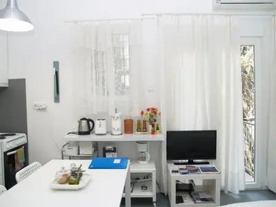 a white room with a table and a television at Newly Renovated Apt in Kolonaki in Athens