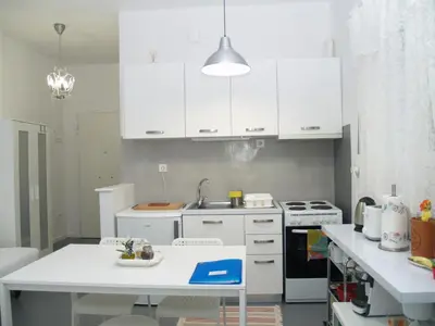 a kitchen with white cabinets and a table in it at Newly Renovated Apt in Kolonaki in Athens