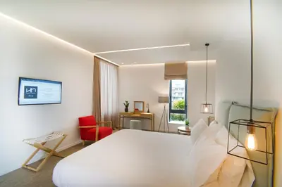 a bedroom with a white bed and a red chair at NLH FIX | Neighborhood Lifestyle Hotels in Athens