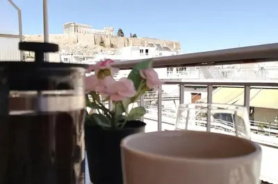 a table with a vase with a flower on a balcony at Acropolis Area Flat with Parthenon Views in Athens