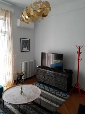 a living room with a table and a flat screen tv at Lux Kolonaki Apartment in Athens