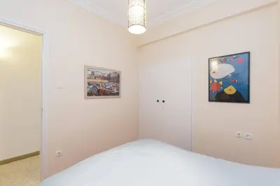 a white bedroom with a bed and two pictures on the wall at Irodotou Grand Apartment in Athens