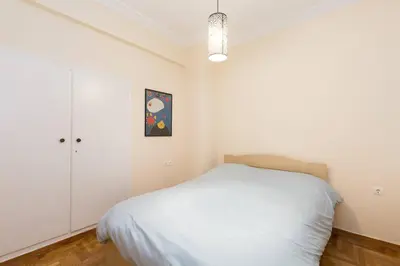 a white bedroom with a bed and a cabinet at Irodotou Grand Apartment in Athens