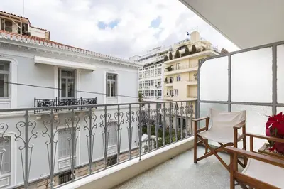 a balcony with a white railing and a chair at Irodotou Grand Apartment in Athens