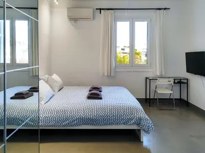 a bedroom with a bed and a desk and windows at KYMA Apartments - Athens Acropolis 8 in Athens