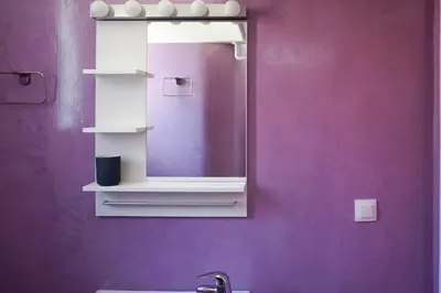 a bathroom with a mirror and a purple wall at KYMA Apartments - Athens Acropolis 8 in Athens