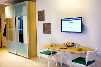 a dining room with a table and a tv on the wall at Emerald Suite in Athens