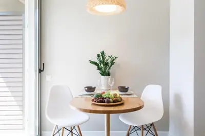 a table with white chairs and a bowl of fruit on it at Homz Studios Faliro in Athens