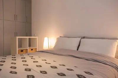 a bedroom with a bed with white sheets and a lamp at Homz Studios Faliro in Athens