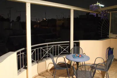 a table and chairs on a balcony at night at Ouranos Apartment in Athens