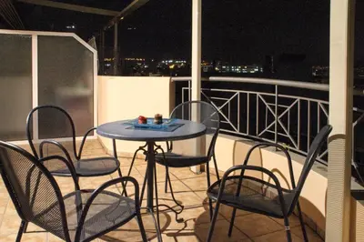 a table and chairs on a balcony at night at Ouranos Apartment in Athens