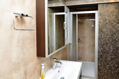 a bathroom with a sink and a mirror and a shower at 165 sm Penthouse Maisonette Apartment in Athens