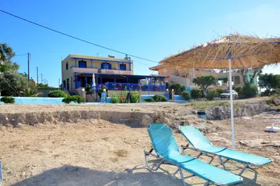 two lounge chairs and an umbrella on the beach at Aiolos in Vaia