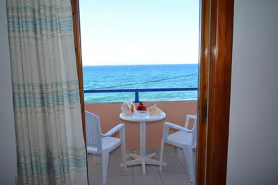 a table and chairs on a balcony with the ocean at Aiolos in Vaia
