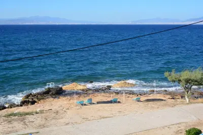 a beach with umbrellas and chairs and the ocean at Aiolos in Vaia