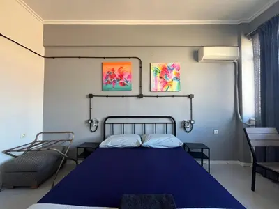 a bedroom with a blue bed and two paintings on the wall at Urban Rooms in Athens