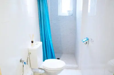 a bathroom with a toilet and a blue shower curtain at Thelma's Apartment in Athens