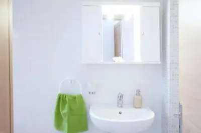 a bathroom with a white sink and a green towel at Thelma's Apartment in Athens