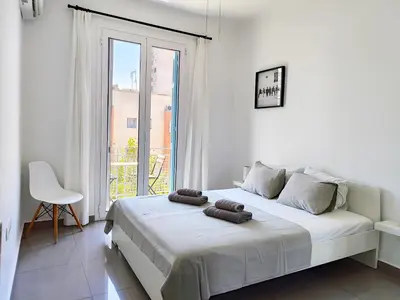 a white bedroom with a large bed and a window at KYMA Apartments - Athens Acropolis 6 in Athens