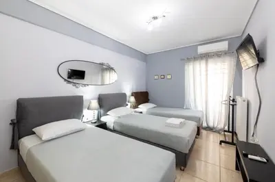 a hotel room with two beds and a mirror at A&J Apartments or Rooms athens airport in Markopoulo