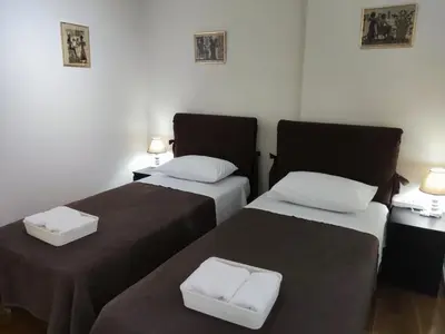 a room with two beds and two tables with lamps at A&J Apartments or Rooms athens airport in Markopoulo