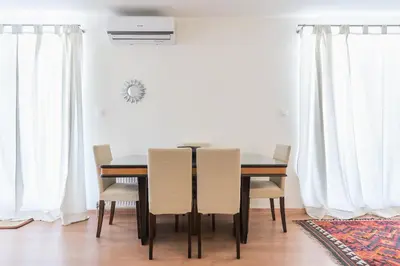 a dining room table and chairs with white curtains at Syntagma Spa with Acropolis View in Athens