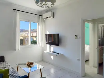 a white living room with a tv on the wall at KYMA Apartments - Athens Acropolis 3 in Athens