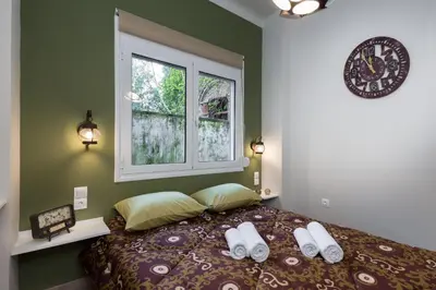 a bedroom with a bed with a clock and a window at Vintage Apartment in the Heart of Plaka in Athens