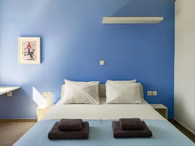 a blue bedroom with a white bed with two brown towels at KYMA Apartments - Athens Acropolis 4 in Athens