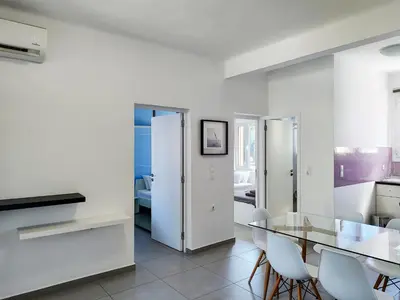a white kitchen with a glass table and chairs at KYMA Apartments - Athens Acropolis 4 in Athens