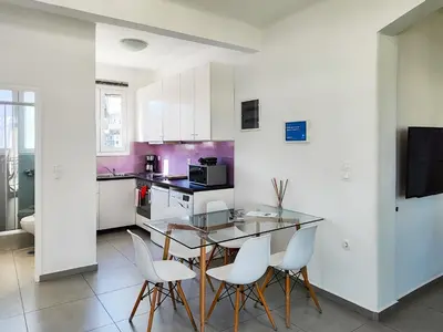 a kitchen with a glass table and white chairs at KYMA Apartments - Athens Acropolis 4 in Athens