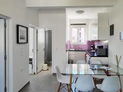 a kitchen with a glass table and white chairs at KYMA Apartments - Athens Acropolis 4 in Athens