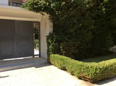 a house with a black door and a bush at Glyfada Centre Studio in Athens