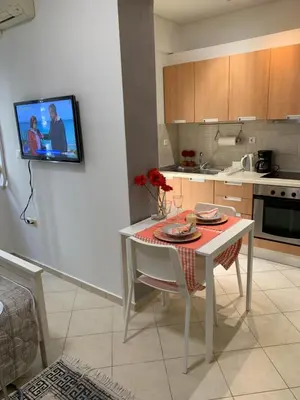 a kitchen with a table and a tv on the wall at Glyfada Centre Studio in Athens