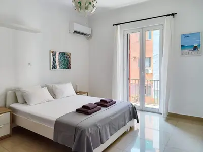 a white bedroom with a bed and a large window at KYMA Apartments - Athens Acropolis 1 in Athens