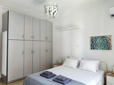a white bedroom with a bed and a chandelier at KYMA Apartments - Athens Acropolis 1 in Athens