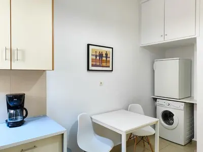 a white kitchen with a table and a washing machine at KYMA Apartments - Athens Acropolis 1 in Athens