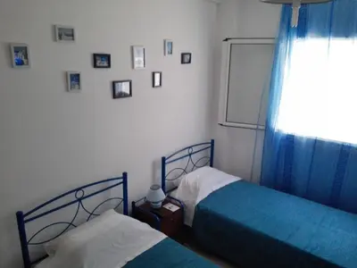 a bedroom with two beds and a window with pictures on the wall at Cosy Apartment Pinotsi in Athens
