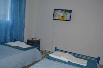 a bedroom with two beds and a tv on the wall at Cosy Apartment Pinotsi in Athens