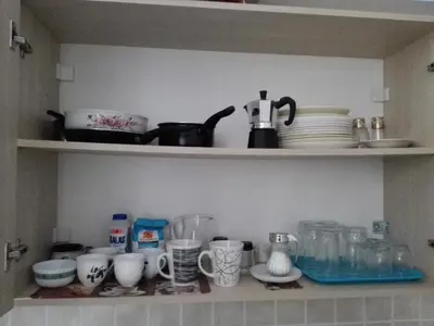 a shelf with cups and dishes on it at Cosy Apartment Pinotsi in Athens