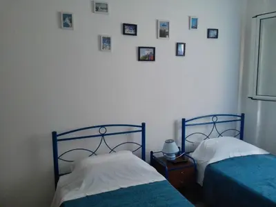 two beds in a room with pictures on the wall at Cosy Apartment Pinotsi in Athens