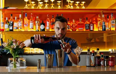 a man is making a drink at a bar at Hotel Lozenge in Athens