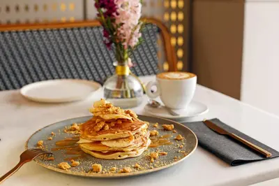 a plate of pancakes on a table with a cup of coffee at Hotel Lozenge in Athens