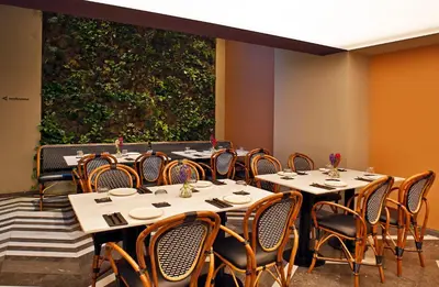 a dining room with tables and chairs and a large wall at Hotel Lozenge in Athens